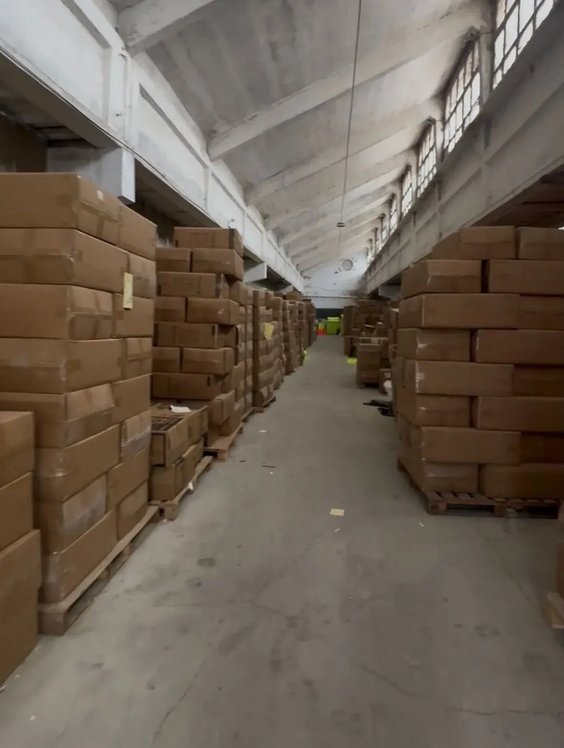 Carton Storage and Warehouse Aisle Stacks of cardboard cartons beside a central warehouse aisle.