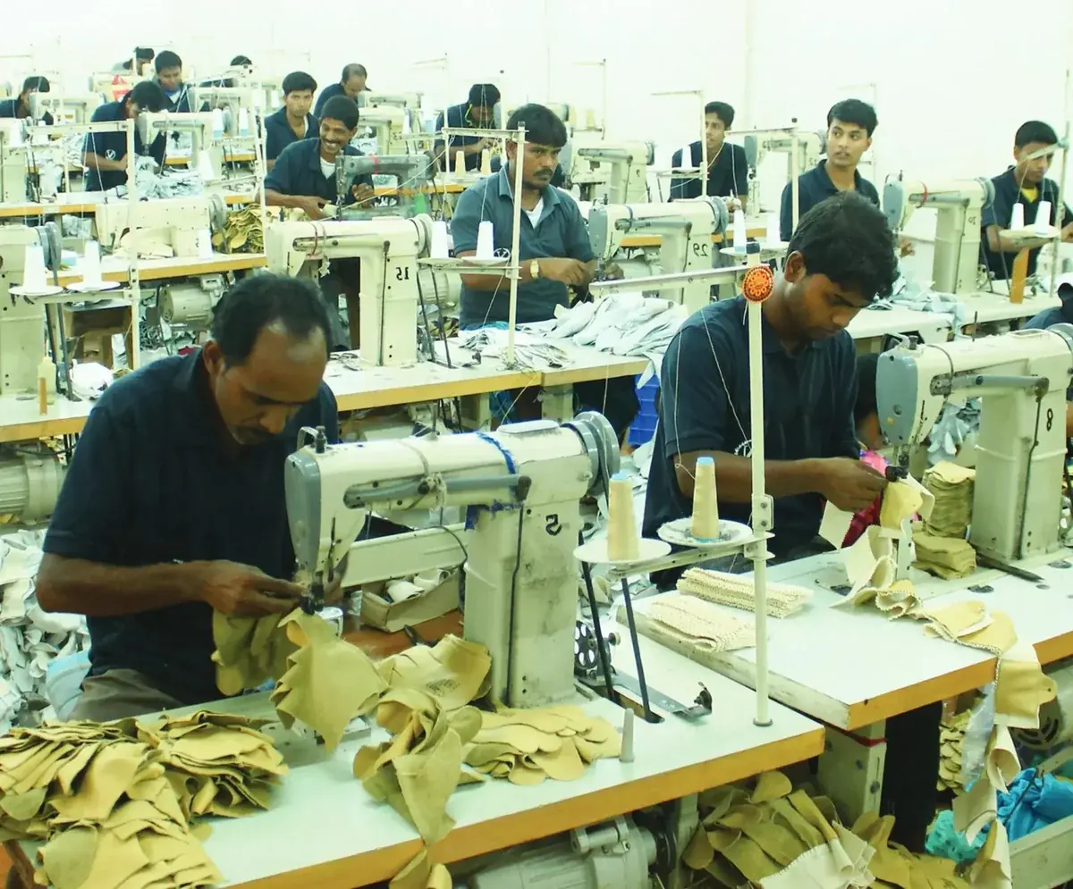Industrial Stitching of Leather Components Sewing-machine operators stitching light-coloured leather components at workstations.