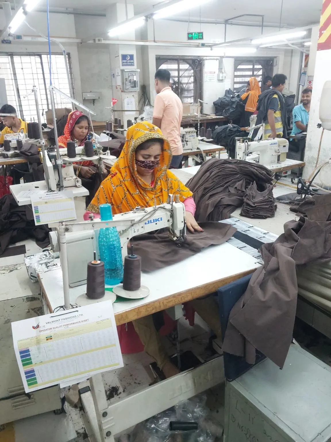 Garment Panel Stitching Workstation An operator guiding brown fabric panels through an industrial sewing machine.
