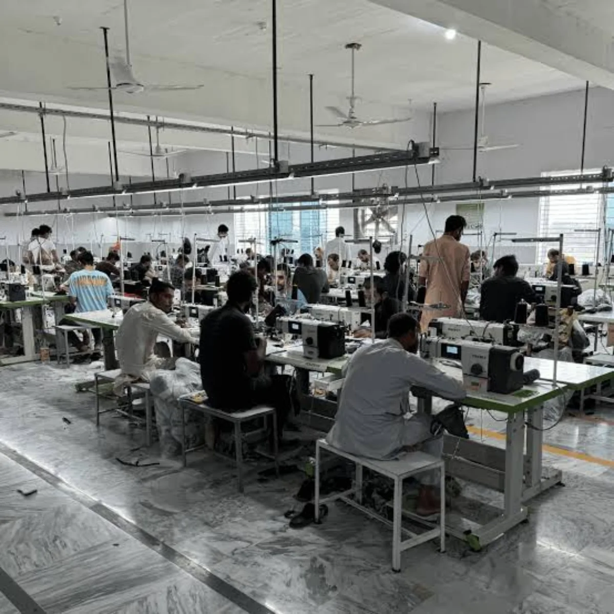 Garment Sewing Workshop and Production Floor Rows of workers operating industrial sewing machines on a garment production floor.