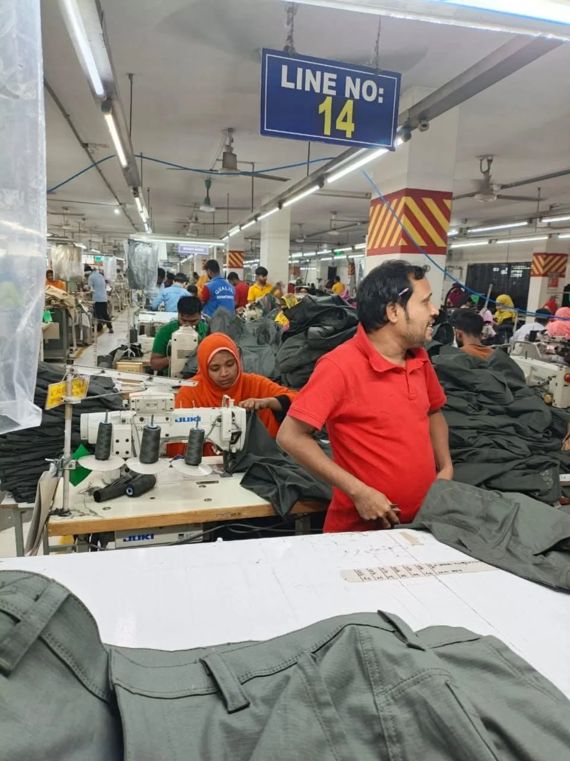 Garment and Trouser Assembly Line Garment sewing line with trouser panels stacked beside industrial machines.