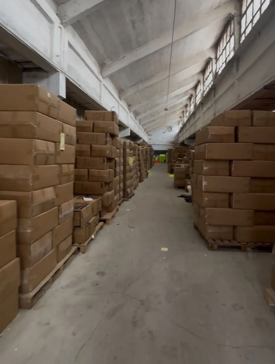Carton Storage and Warehouse Aisle Stacks of cardboard cartons beside a central warehouse aisle.