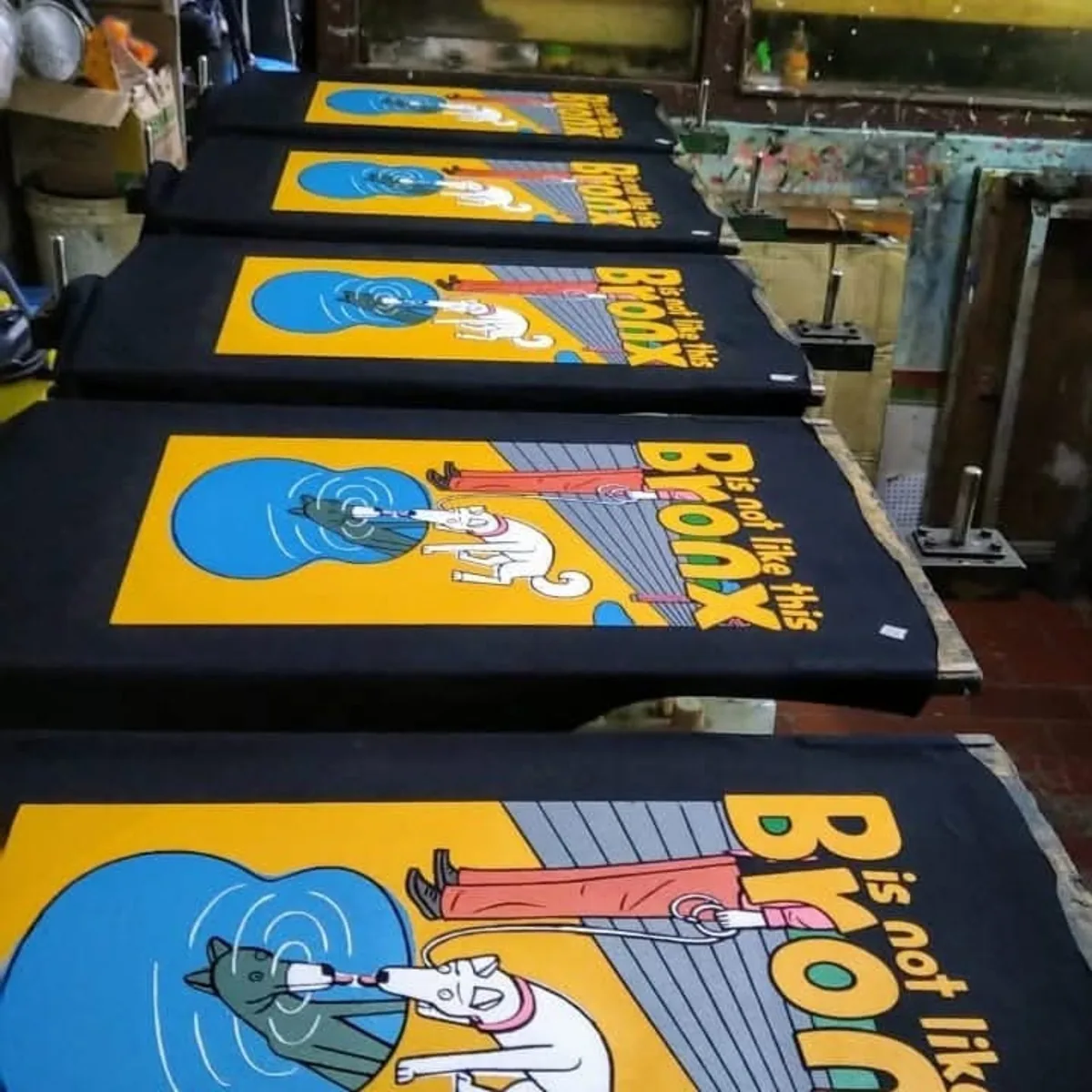 Graphic Textile Screen Printing on Platens Black fabric panels with colourful printed graphics arranged on screen-printing platens.