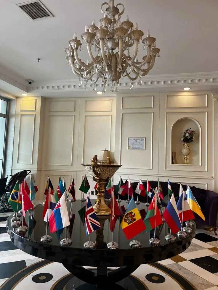 International Table Flags Display | ZESTLET Flags & Banners Small international flags on metal desk stands arranged around a decorative centrepiece on a round table.